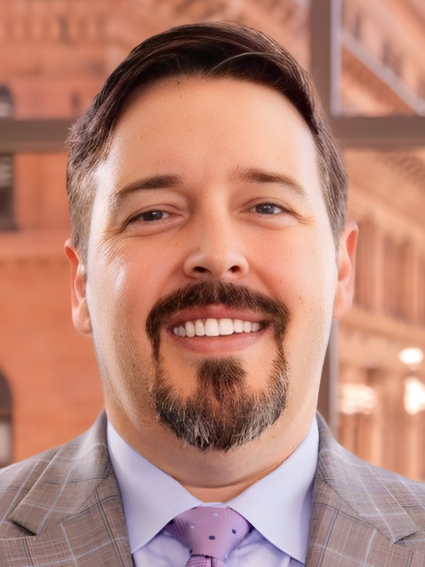 Ben Neely smiling in a suit and tie